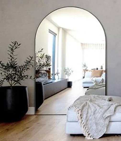 Arched full-length floor mirror in a styled living room — mirror care booklet